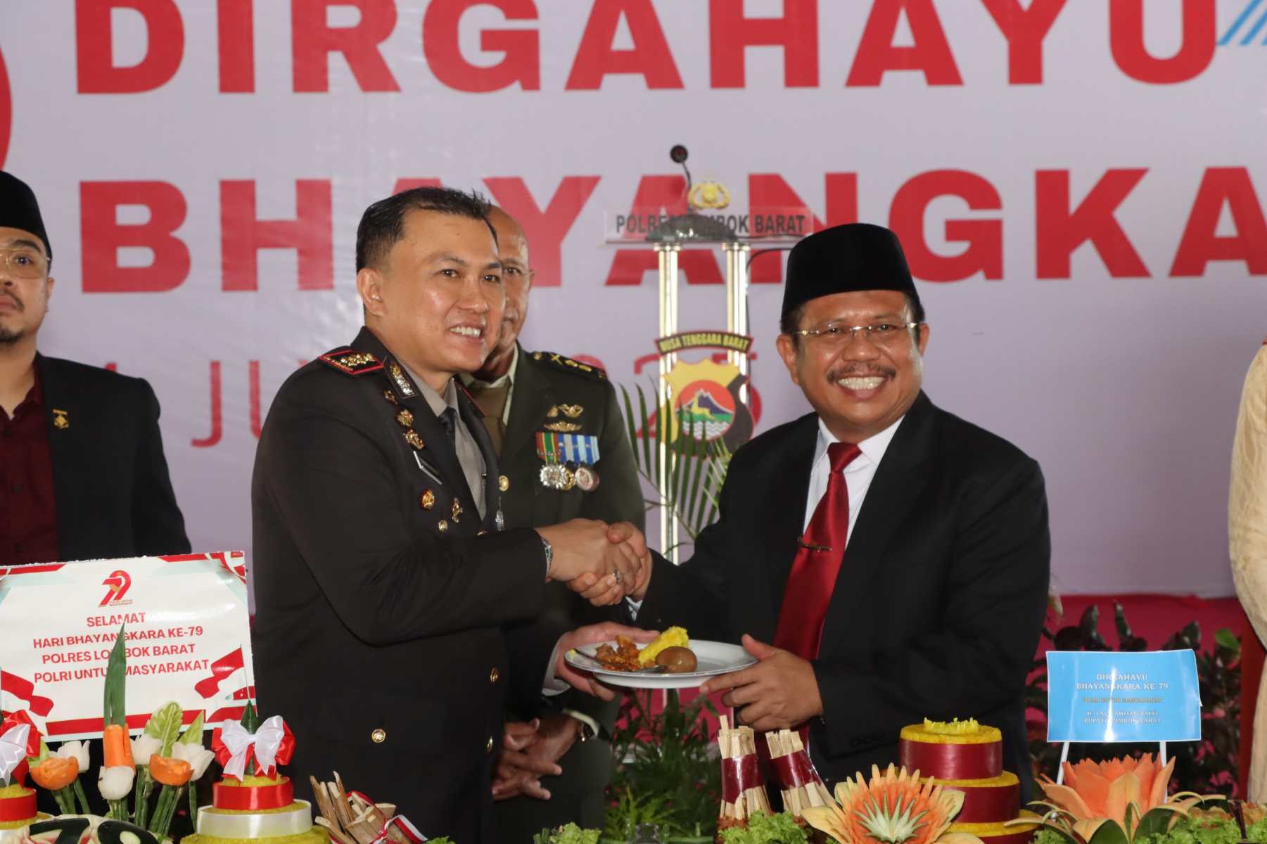 Lombok Barat, NTB – Kepolisian Republik Indonesia (Polri) merayakan ulang tahunnya yang ke-79 pada 1 Juli 2025. Di Lombok Barat, peringatan Hari Bhayangkara kali ini selain dengan menggelar upacara, juga ditandai dengan acara tasyakuran yang penuh makna. Menegaskan kembali komitmen Polri untuk terus meningkatkan kualitas pelayanan kepada masyarakat. Pada Selasa (1/7/2025), suasana di bencingah kantor Bupati Lombok Barat tampak semarak dengan kehadiran para pejabat dan tokoh masyarakat. Acara Tasyakuran Hari Bhayangkara ke-79 ini digelar di Jalan Soekarno-Hatta, Kelurahan Dasan Geres, Kecamatan Gerung, Kabupaten Lombok Barat, menjadi momentum penting. Untuk mempererat sinergitas antara Polri, TNI, pemerintah daerah, dan seluruh elemen masyarakat. Meningkatkan Pelayanan dan Memperkuat Sinergi Dalam sambutannya yang penuh semangat, Kapolres Lombok Barat, AKBP Yasmara Harahap, S.I.K., menyampaikan bahwa Hari Bhayangkara ke-79 mengusung tema ‘Polri untuk Masyarakat’. Menurutnya, tema ini bukan sekadar slogan, melainkan sebuah amanah untuk terus berbenah. "Dalam rangka Hari Bhayangkara ke-79 tahun 2025 dengan tema Polri Untuk Masyarakat, tentunya kita harus meningkatkan kualitas diri sebagai insan Bhayangkara. Untuk melaksanakan pelayanan maksimal kepada masyarakat," ujar AKBP Yasmara. Ia menekankan pentingnya introspeksi diri dan peningkatan kinerja untuk memberikan pelayanan terbaik. "Polri tegak berdiri dan berkomitmen untuk menjadi lebih modern dan terpercaya," tambahnya. Menurut Kapolres, semua upaya ini bertujuan utama untuk menjaga stabilitas keamanan dan ketertiban masyarakat (kamtibmas) di Provinsi NTB agar tetap kondusif. Ia juga menjelaskan bahwa rangkaian kegiatan dalam rangka Hari Bhayangkara di Polres Lombok Barat sudah dimulai sejak awal Juni. Dengan berbagai kegiatan yang menyentuh langsung masyarakat. AKBP Yasmara Harahap juga menyampaikan rasa terima kasihnya kepada semua pihak yang telah mendukung tugas-tugas Polri. "Terima kasih kepada Bapak Bupati yang telah mendukung tugas-tugas kamtibmas. Tidak mungkin kami berjalan sendiri tanpa dukungan dari Pemda dan seluruh elemen masyarakat," tegasnya. Kolaborasi Pemerintah dan Polri untuk Pelayanan Optimal Senada dengan Kapolres, Bupati Lombok Barat, H. Lalu Ahmad Zaini, S. Si., M.T., juga memberikan apresiasi setinggi-tingginya kepada jajaran kepolisian. Dalam pernyataannya, Bupati mengucapkan selamat Hari Bhayangkara dan menekankan pentingnya sinergi antara pemerintah daerah dan Polri. "Atas nama Pemerintah Kabupaten Lombok Barat, kami menyampaikan dirgahayu Kepolisian," kata Bupati Lalu Ahmad Zaini. "Sinergitas dan kolaborasi akan terus kita tingkatkan agar pelayanan kepada masyarakat akan terus dapat dioptimalkan,” imbuhnya. Pernyataan ini menunjukkan komitmen kuat dari pemerintah daerah untuk terus bekerja sama dengan Polri demi kesejahteraan dan keamanan masyarakat Lombok Barat. Momen Kebersamaan dan Apresiasi Setelah sambutan, acara dilanjutkan dengan momen simbolis pemotongan kue dan tumpeng. Kapolres Lombok Barat bersama Ibu Ketua Bhayangkari, Bupati Lombok Barat, perwakilan Dandim 1606, Wakil Bupati, Sekda, dan Ketua DPRD secara bersama-sama melakukan pemotongan tumpeng, melambangkan kebersamaan dan rasa syukur. Kemeriahan acara juga terasa saat pembacaan dan penyerahan hadiah bagi para pemenang lomba-lomba yang diselenggarakan dalam rangka memeriahkan Hari Bhayangkara ke-79. Berbagai lomba tersebut tidak hanya menjadi ajang silaturahmi, tetapi juga menunjukkan partisipasi aktif masyarakat dalam perayaan hari jadi korps Bhayangkara. Peringatan Hari Bhayangkara ke-79 ini menjadi momentum refleksi bagi seluruh jajaran Polres Lombok Barat untuk terus berbenah dan meningkatkan kualitas diri. Turut hadir pula dalam acara ini, Ketua Cabang Bhayangkari Lombok Barat, Ny. Citra Yasmara, bersama jajaran pengurus. Serta perwakilan dari Kodim 1606 Mataram, Letkol Inf. Abdul Haris S.H. M.H. Selain itu, hadir pula Wakil Bupati Lombok Barat, Hj. Nurul Adha, S.THI, Sekda Kabupaten Lombok Barat, H. Ilham S.Pd M.Pd., Ketua DPRD Kabupaten Lombok Barat, Lalu Ivan Indaryadi, serta perwakilan dari Pengadilan Negeri Mataram dan Kejaksaan Negeri Mataram. Kehadiran para pimpinan OPD, tokoh agama, tokoh masyarakat, dan tokoh adat menunjukkan soliditas dukungan terhadap tugas-tugas kepolisian.